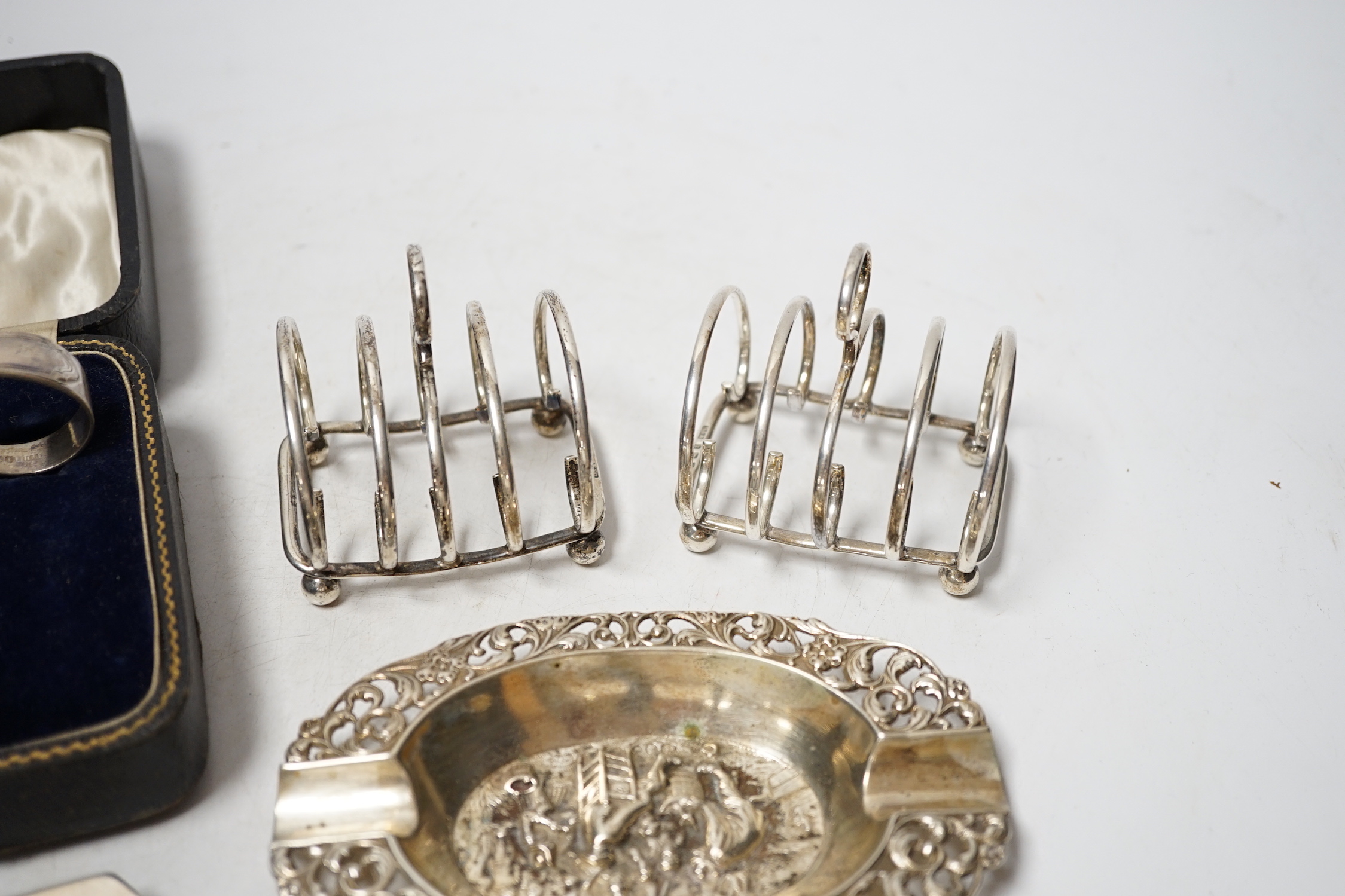 A Dutch white metal ashtray, with pierced border, 13.1cm and one other silver hexagonal ashtray?, a pair of small silver toastracks, two silver napkin rings and six items of silver flatware, including pair of Irish condi